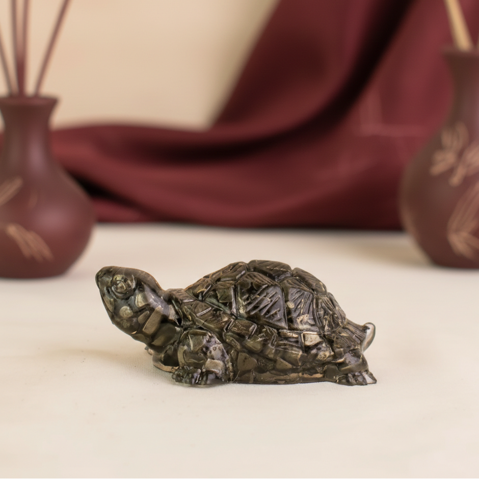 Pyrite turtle figurine on a beige surface with blurred background